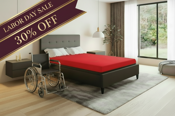 A modern bedroom scene showing a dark gray upholstered bed with a bright red mattress, alongside a wheelchair in the foreground. A large diagonal sale banner reads 'LABOR DAY SALE 30% OFF'.